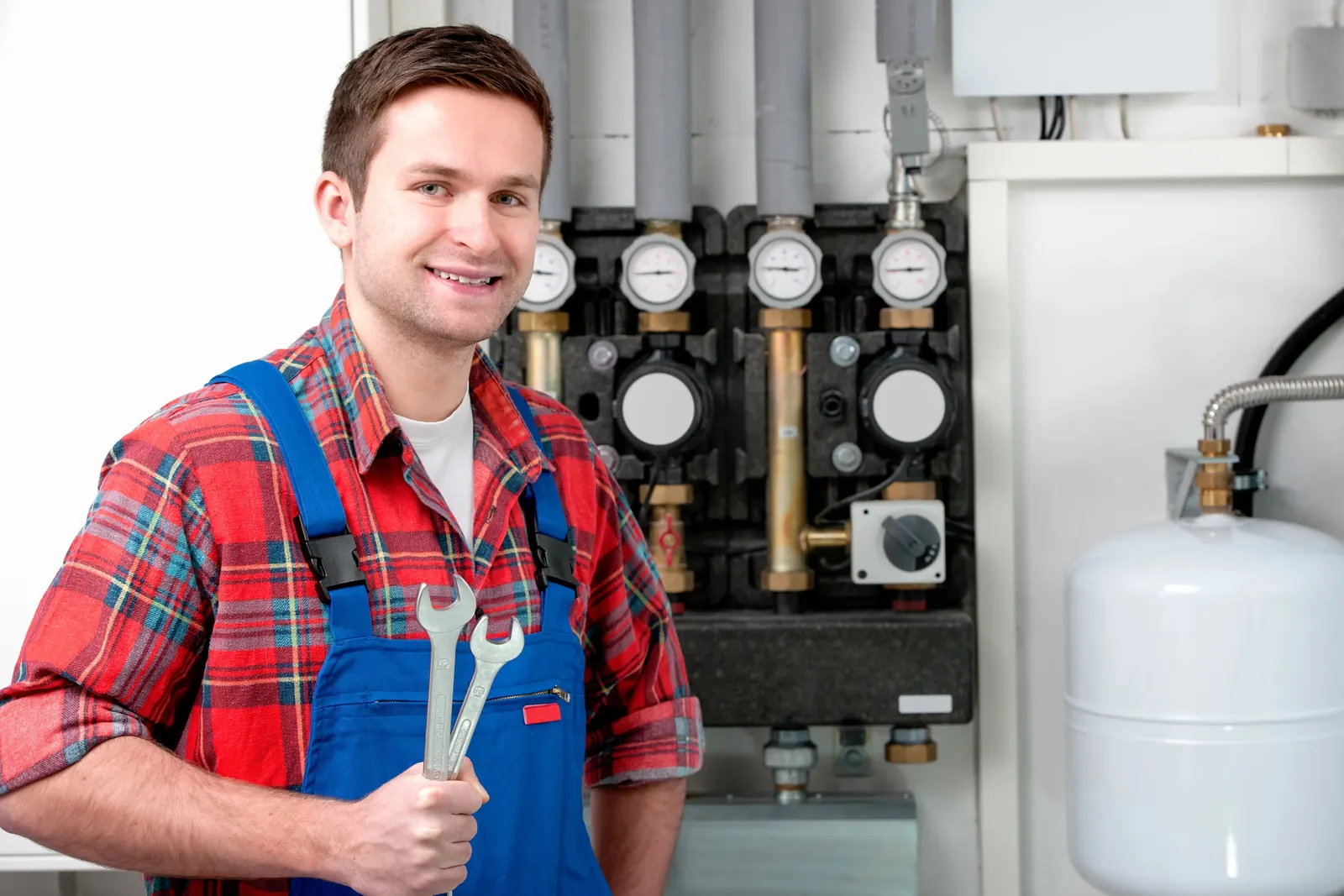 Technicien devant les circulateurs et collecteurs d'une installation de chauffage thermodynamique